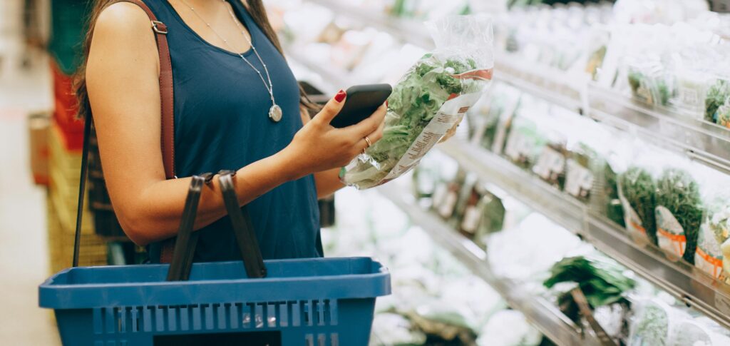 Kvinne sjekker pris på vare i grønnsaksavdelingen
